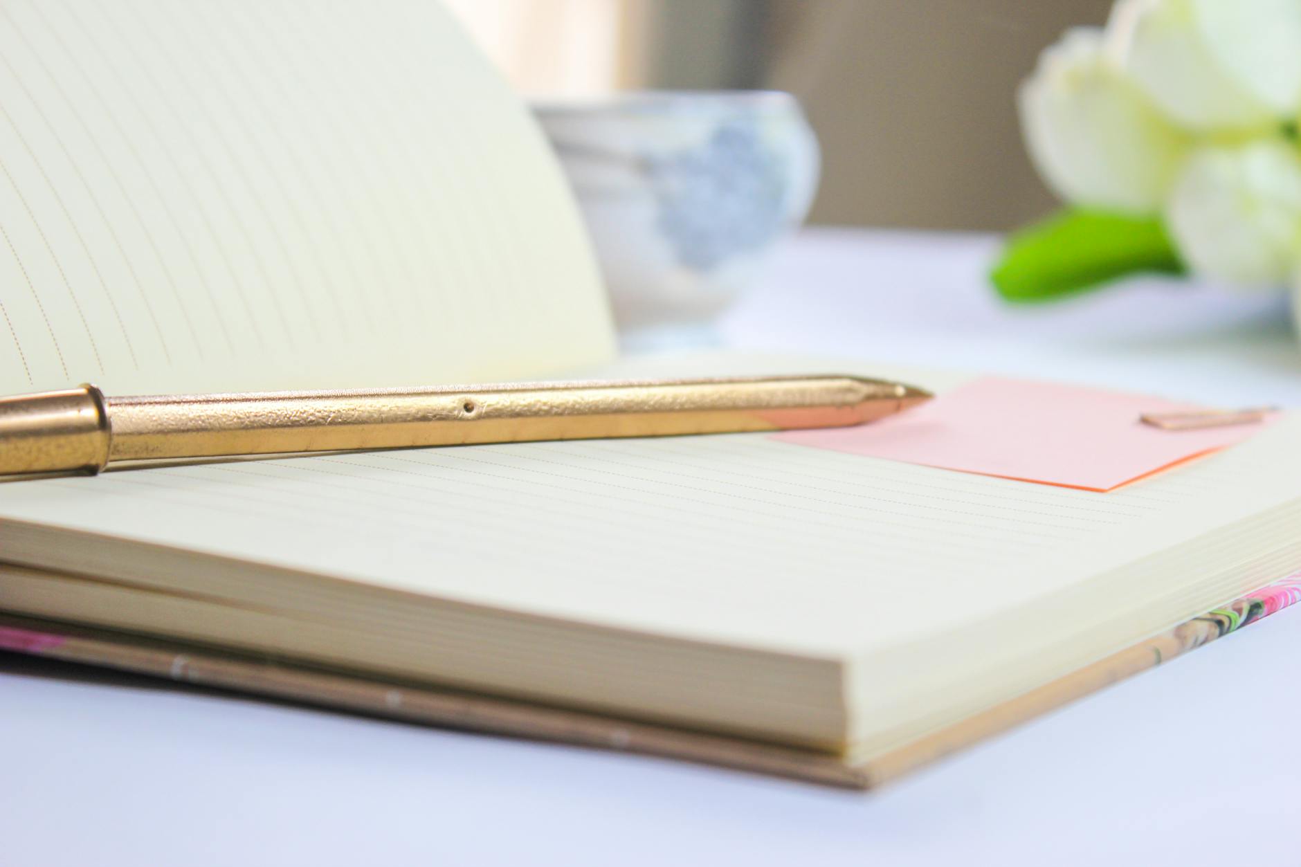 elegant notebook with gold pen and white flowers